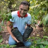 Sol y cafe Coop member smiles while planting young coffee trees on organic Peruvian farm.