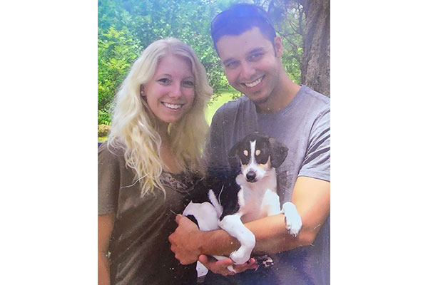 Jennifer and her husband Mischa smiling with their newly adopted puppy, Brock.