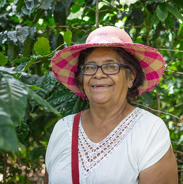 Maria Transito Argueta, a Coffee Producer from Honduras smiling wearing a pink sun hat on her farm "La Encantata".