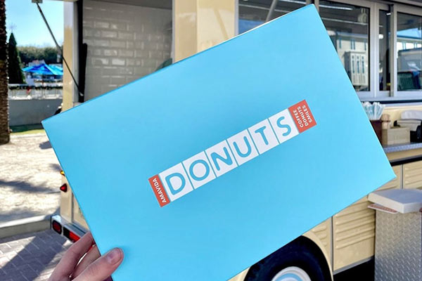 New blue, white and coral Amavida Donuts box in front of the donut truck in Seaside, FL.